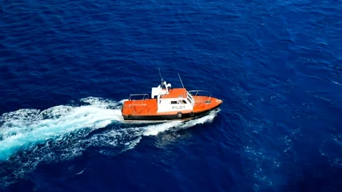 Orange pilot boat turning around the cargo vessel for entering to the port Stock Footage 158788041