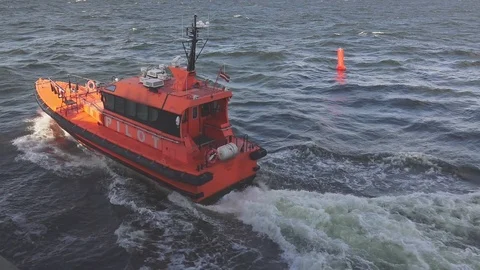 Orange pilot launch sails along sea water surface past buoy Stock Footage 121117422