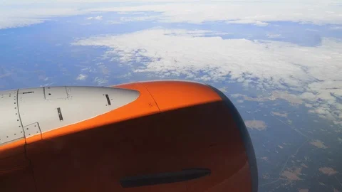 An orange plane flies over curly clouds through which the landscape is visible Stock Footage 126612455