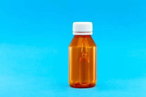 Orange plastic bottle with a yellow cap and an ampoule with vaccine inside. Stock Photos