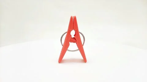An orange plastic clothes pin or clothes peg for isolated rotating on white Stock Footage 304688513