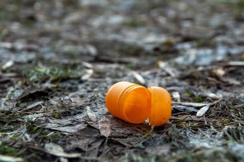 Orange plastic egg container as litter on the ground Stock Photos