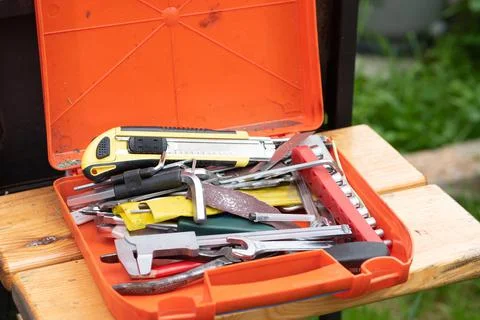 Orange plastic toolkit with instruments lies on wooden bench Stock Photos