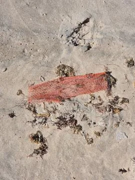 Orange plastic trash in the sand a glaring contrast to the beach’s natural Stock Photos