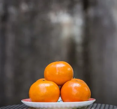 Orange in plate with gray background. Fotos Stock