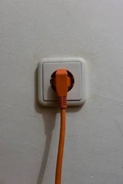 Orange plug connected to a white socket Stock Photos