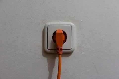 Orange plug connected to a white socket Stock Photos