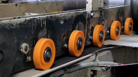 Orange polyurethane guide wheels feeding corrugated cardboard sheet into in.. 库存影片 337670221