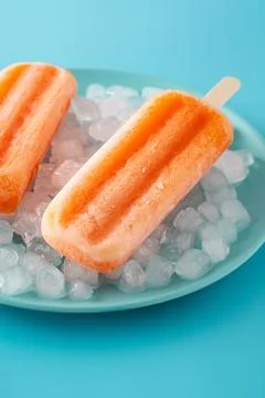 Orange popsicles on blue plate Stock Photos