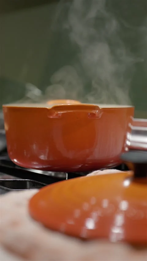Orange pot with vegetables boiling on gas stove in home kitchen Видео 220767942