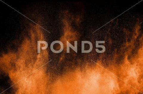 Orange powder explosion on black background. Orange color dust splash. Stock Photos