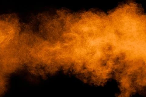 Orange powder explosion on black background. Orange color dust splash. Stock Photos
