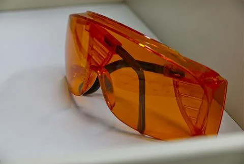 Orange protective glasses with black arms on clean white surface Stock Photos