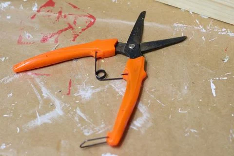 Orange pruning shears on brown paper with paint Stock Photos