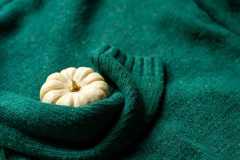 Orange pumpkin near a stack of knitted sweaters on a knitted blanket Foto stock