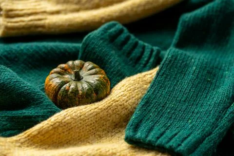 Orange pumpkin near a stack of knitted sweaters on a knitted blanket Foto stock