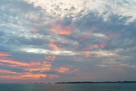 Orange rays of the sun at sunset with clouds and sea Stock Photos