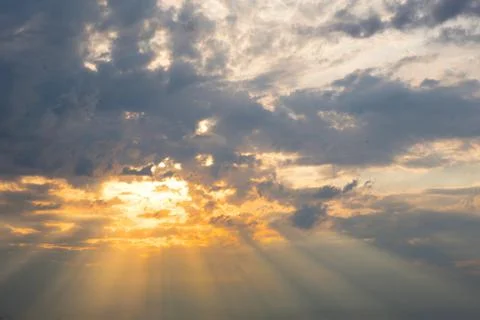 Orange rays of the sun through cumulus clouds in the sky at sunset in summer. 스톡 사진