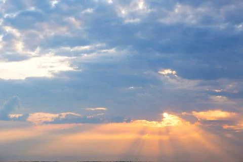 Orange rays of the sun through cumulus clouds in the sky at sunset in summer. Stock-Fotos