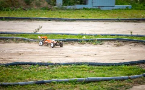 Orange RC buggy going quickly throuh a turn on an outdoor track Stock Photos