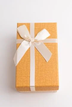 Orange rectangular gift box decorated with elegant white ribbon bow isolate.. Stock Photos