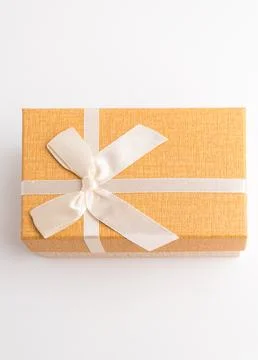 Orange rectangular gift box decorated with elegant white ribbon bow isolate.. Stock Photos