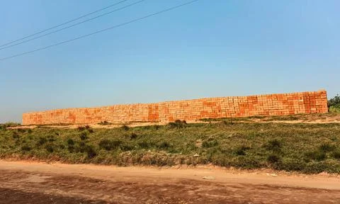 Orange red bricks made from local clay arranged in wide stack, ready for b... Stockfoto's