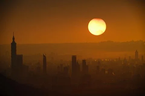 The orange-red sunset is covered by clouds as it moves towards the horizon. Stock Photos