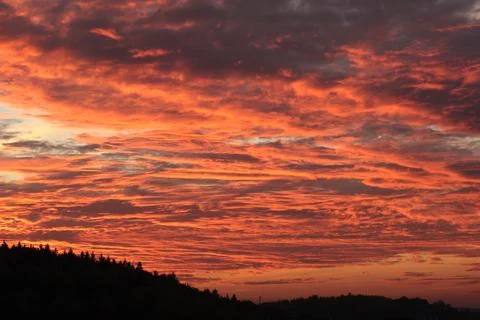 Orange, red sunset over forest and village. Romantic dramatic background for Stock Photos