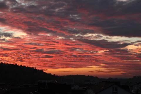 Orange, red sunset over forest and village. Romantic dramatic background for Stock Photos