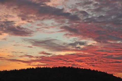 Orange, red sunset over forest and village. Romantic dramatic background for Stock Photos