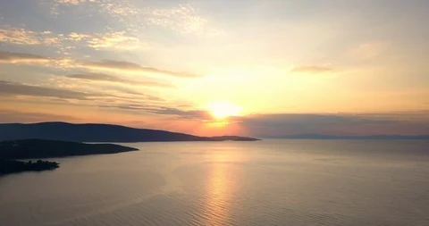 Orange reflection of sunset behind clouds over the sea Stock Footage 107981386