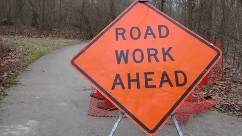 Orange road work ahead caution sign on trail in nature park Video stock 147702366
