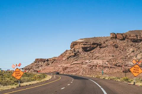 Orange Road work ahead caution signs on empty highway in southwest Stock Photos