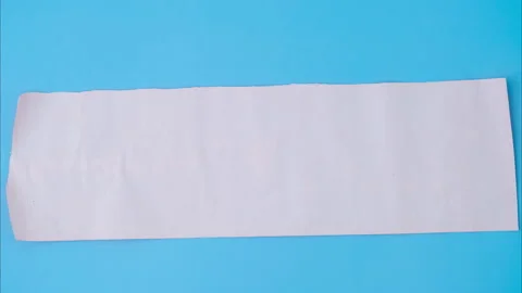 Orange rolled square paper is spread out into a blank white sheet on blue  Stock Footage 251411259