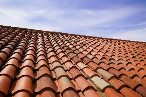 Orange roof tile pattern over blue and cloudy spring sky day Stock Photos