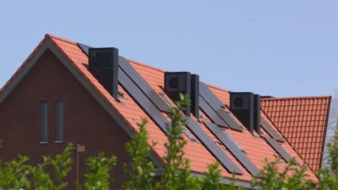 Orange rooftops with black solar panels and chimney integrated heat pumps Stock Footage 243067596