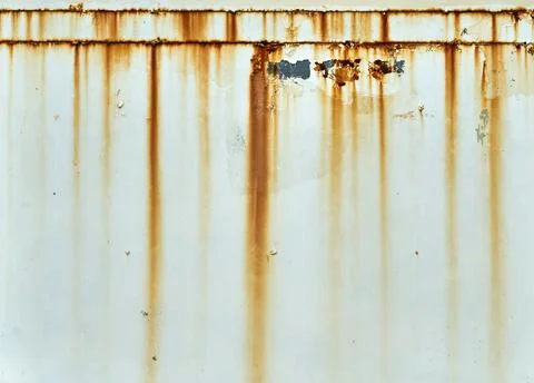 Orange rust streaks down a white wall Stock Photos