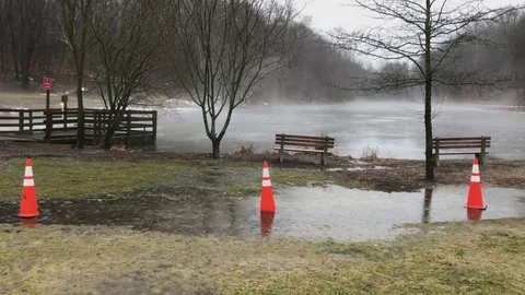 Orange Safety Cones in Puddle By Pond During Winter Rainstorm Stock Footage 85195159