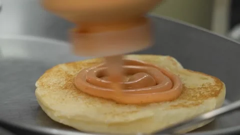 Orange Sauce Being Squeezed Onto a Toasted Bun Stock Footage 331633983