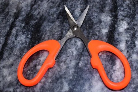 Orange scissors on a dark background Stock Photos