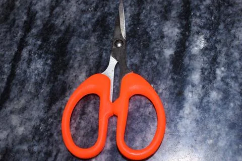 Orange scissors on a dark background Stock Photos