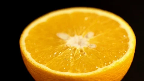 Orange in a section close up. Well lit orange rotates around itself on a black Stock Footage 86317135