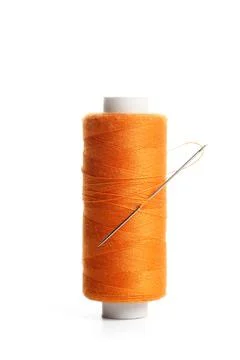 Orange sewing thread spool with needle isolated on white background, closeup Stock Photos