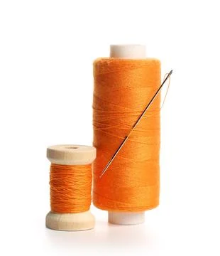 Orange sewing thread spools with needle isolated on white background, closeup Stock Photos