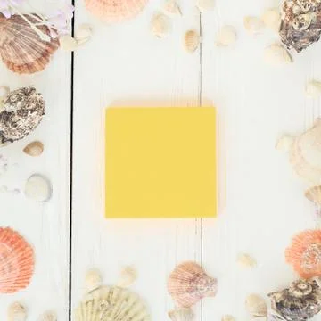 Orange sheet of paper and seashells on a wooden background.Travel background Stock Photos