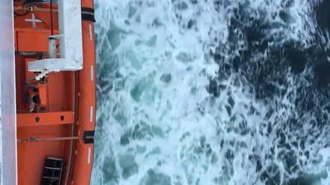 Orange ship sailing on the cold blue ocean, with waves and foam, aerial view Stock Footage 118989739