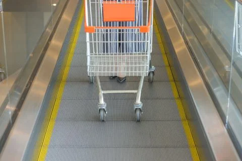 Orange shopping trolley going down the escalator Stock-Fotos