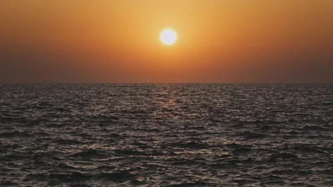 Orange sky and sun setting over calm waves of a gray sea or ocean. Tranquil, zen Stock Footage 171814298