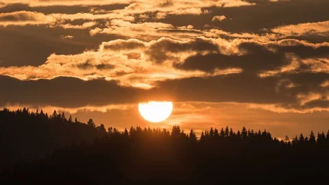Orange sky with sun and clouds moving at sunset over forest Time lapse Stock Footage 94713358